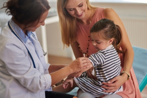 Child receiving a vaccine while holding stuffed animal